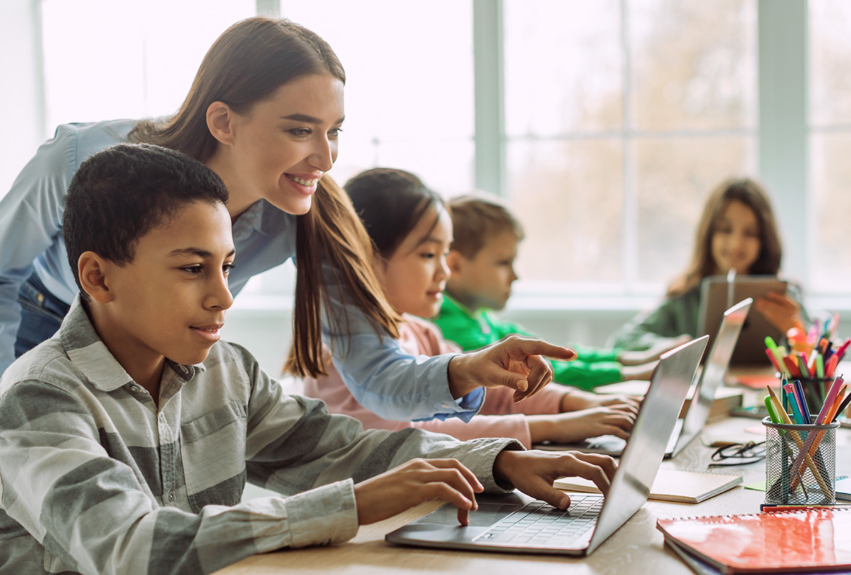 Students and teacher in classroom with laptops